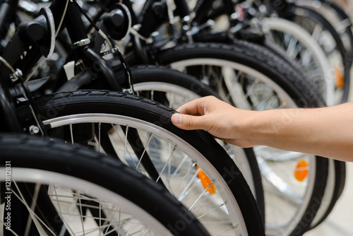 Closeup on person hand checking bicycle tire, shop factory background.