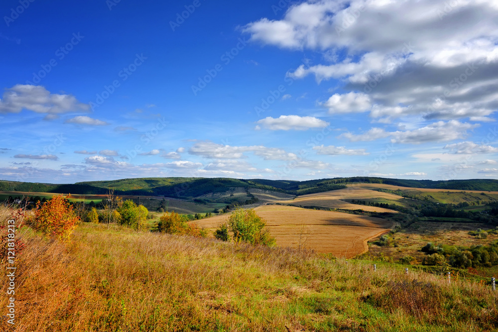Autumn hills on a sunny day with clouds in the blue sky