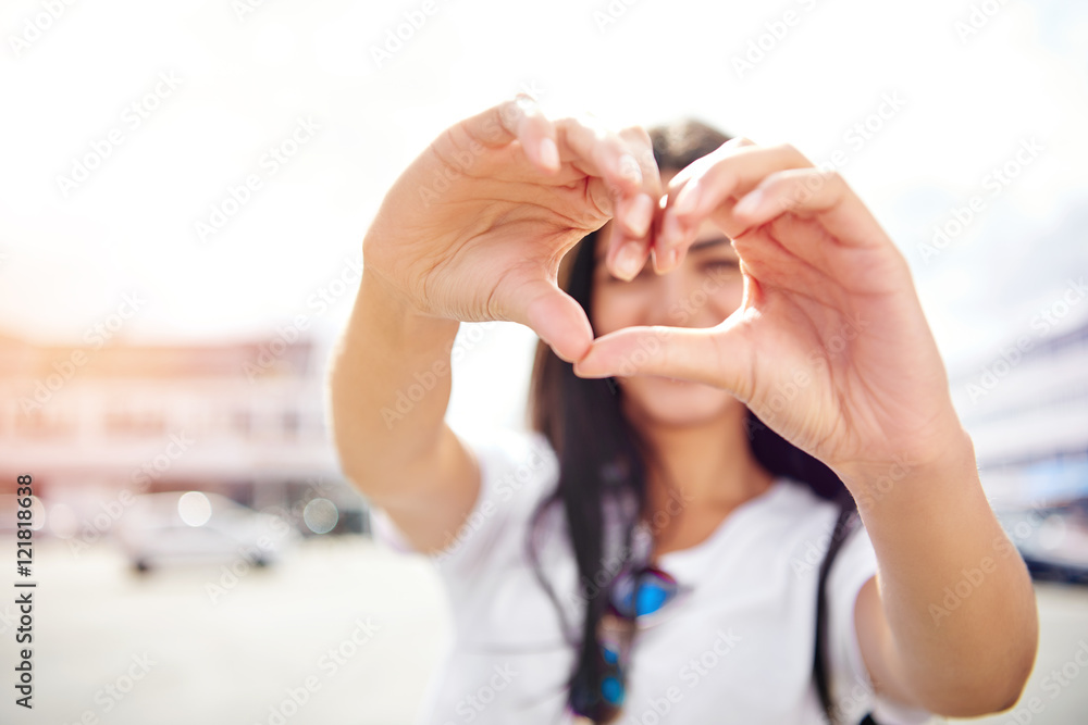 Fototapeta premium Romantic young woman making a heart gesture