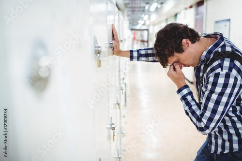 Sad student leaning on locker