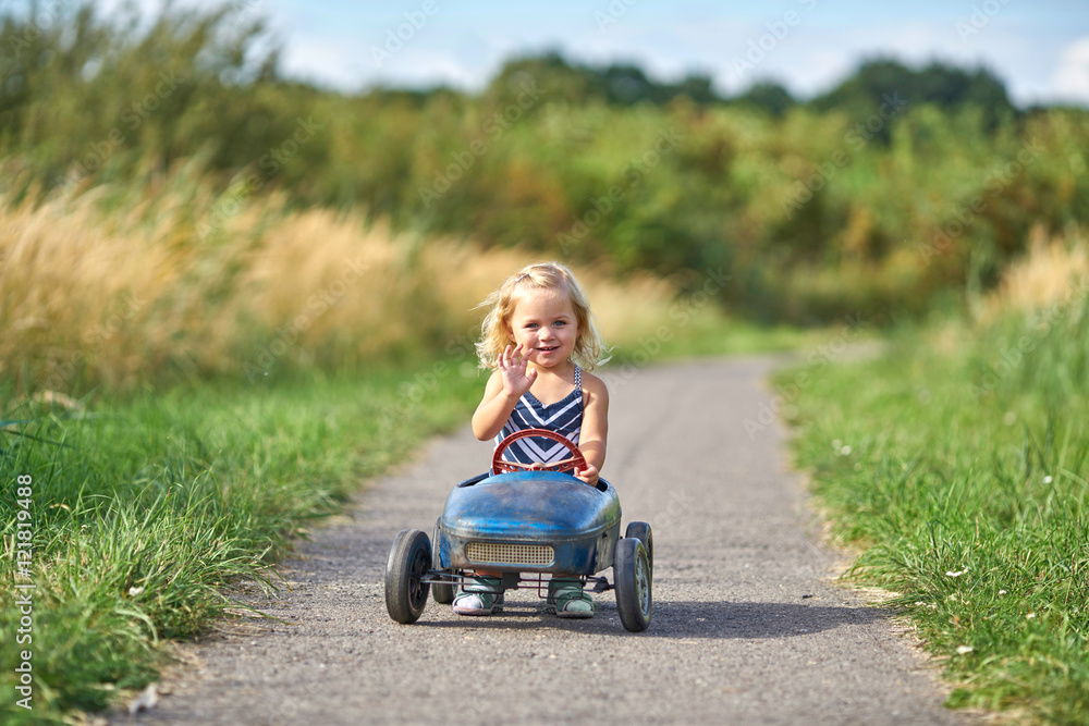 kleines Mädchen hat Spaß beim Fahren mit dem Tretauto kleines Mädchen hat Spaß beim Fahren mit dem Tretauto