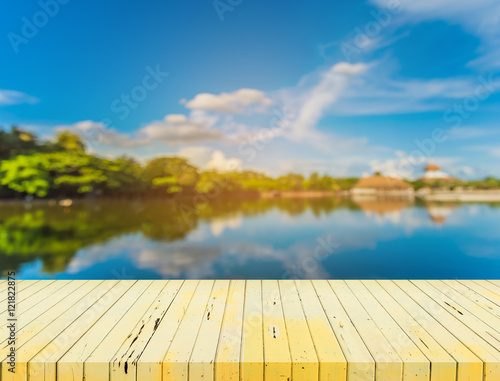   wooden table with blur image of lake. © coffmancmu