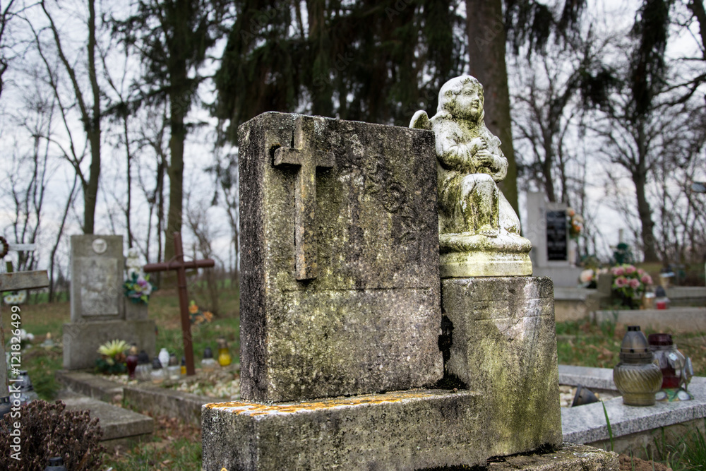 Graves, tombstones and crucifixes on traditional cemetery. Votive candles lantern and flowers on tomb stones in graveyard. All Saints' Day.All Souls' Day. Gravestones in village Tvrdomestice, Slovakia