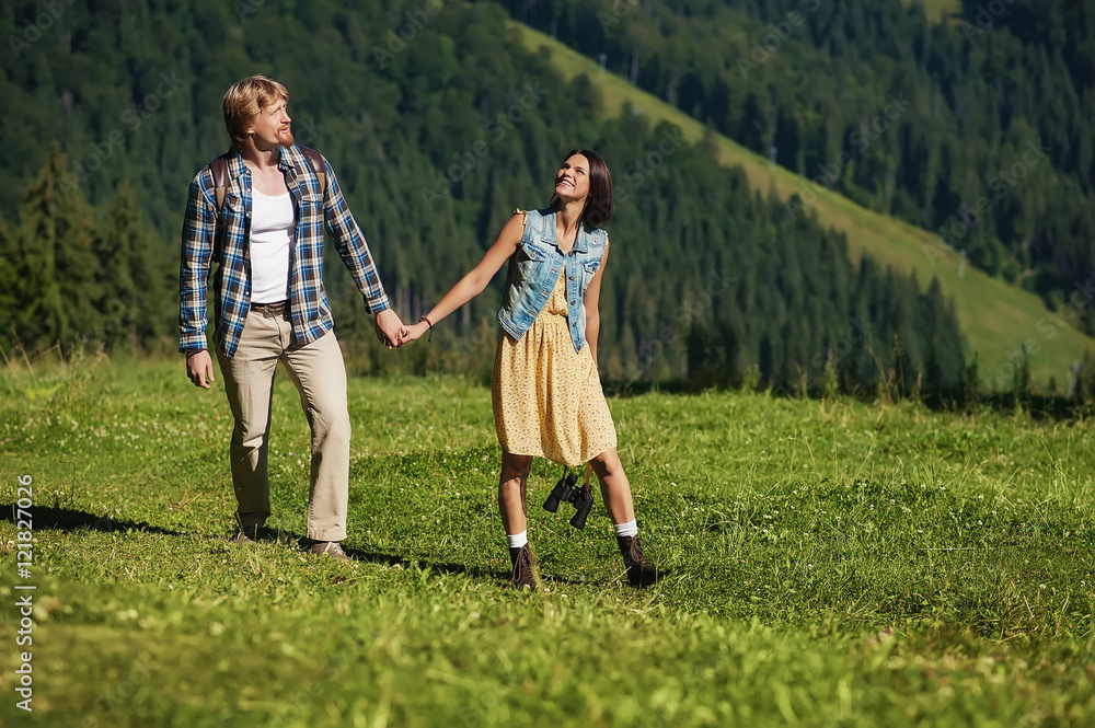 young couple in love dressed in country style holding hands and walking on mountain high