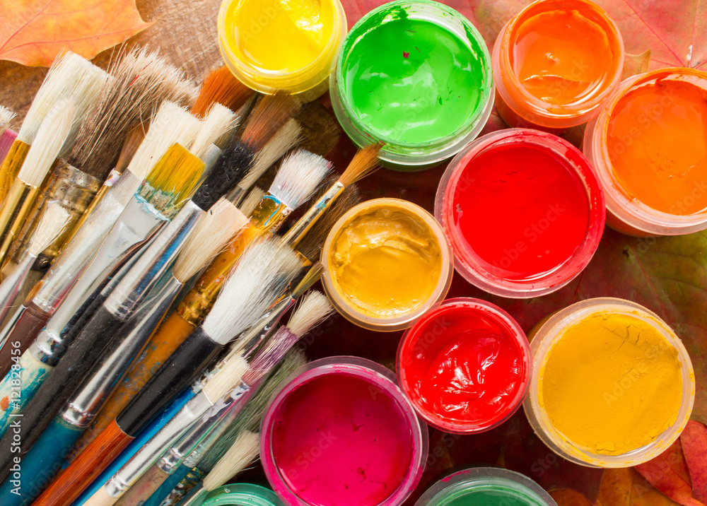 Colorful paints, brushes, palette, autumn leaves on wood background. Autumn still-life. The workplace of the artist. Banner for the school. Colorful paints, brushes, palette, autumn leaves on wood background. Autumn still-life. The workplace of the artist. Banner for the school.