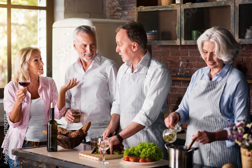 Middle-aged woman telling stories to elderly friends while cooking lunch