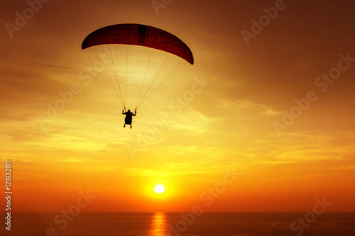 Silhouette of skydiver on background sunset