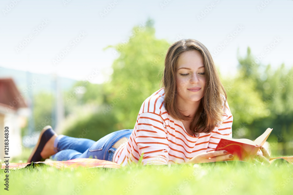 Full length shot of a beautiful young woman reading book while relaxing at park. Full length shot of a beautiful young woman reading book while relaxing at park.
