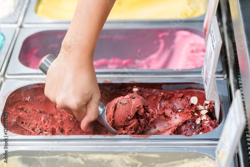 Young saleswoman in an ice cream parlor takes a scoop of ice cream
