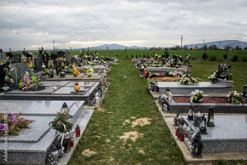 Graves, tombstones and crucifixes on traditional cemetery. Votive candles lantern and flowers on tomb stones in graveyard. All Saints' Day.All Souls' Day. Gravestones in village Tvrdomestice, Slovakia