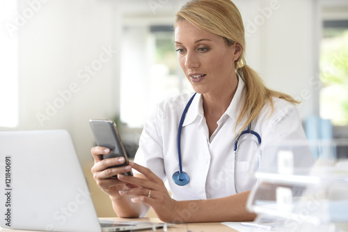 Portrait of nurse in office using smartphone