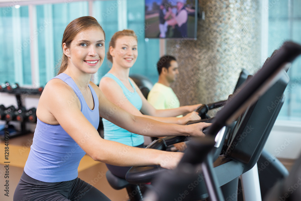 Smiling young people training on exercise machines Smiling young people training on exercise machines