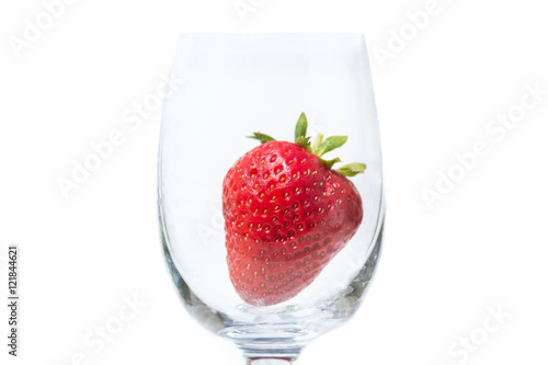 Red and ripe strawberry in wineglass on a white background
