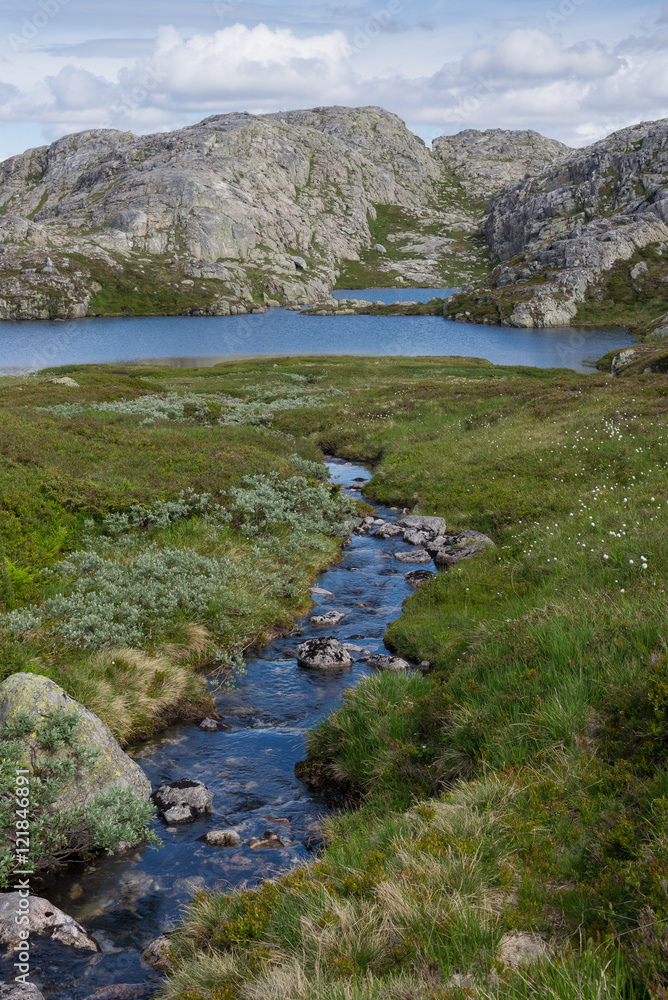 Scenic view of mountain stream and lake with mountain peaks in the background, Rogaland, Norway. 