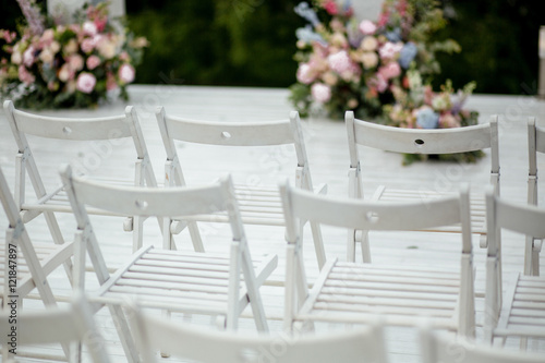 White garden chairs stand in a ray waiting for the wedding cerem
