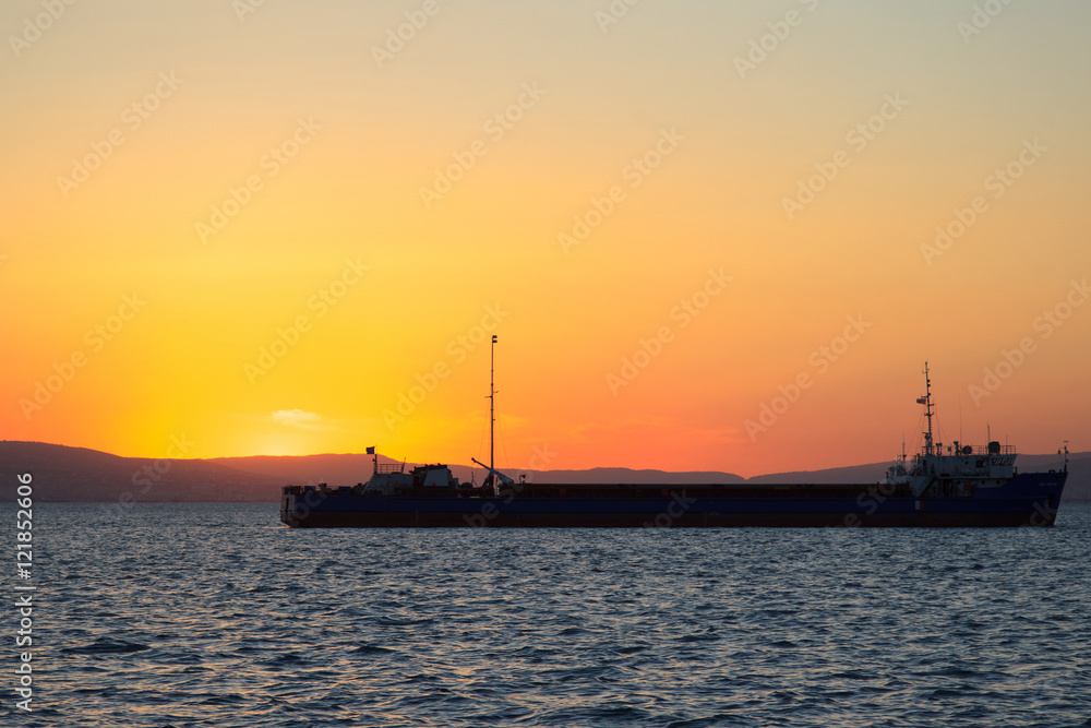 Sunset at sea with cargo ships in the background