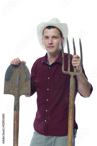A farmer in a hat with a shovel and pitchfork in hand