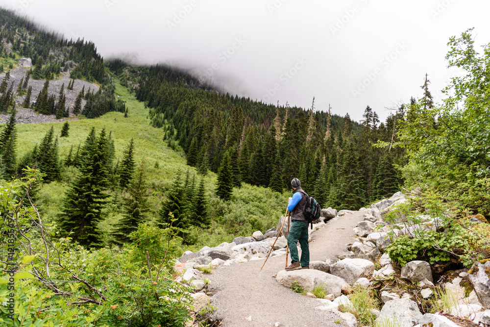 Hiker with backpack looking at amazing mountain view. Hiker motivated to achieve the summit. Trekking, travel, freedom and tourism concept. Fitness and healthy lifestyle.