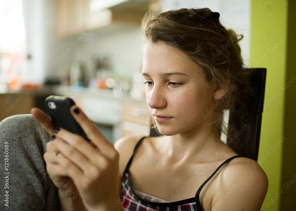 Authentic portrait of teenager girl using smart phone at home Authentic portrait of teenager girl using smart phone at home