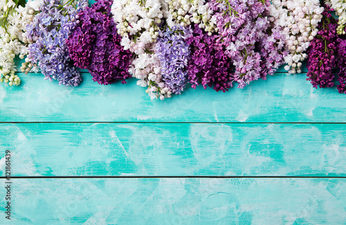 Bunch of lilac flowers on a turquoise wooden background Top view copy space photo