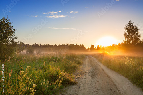 summer rural landscape with sunrise , fog and the road