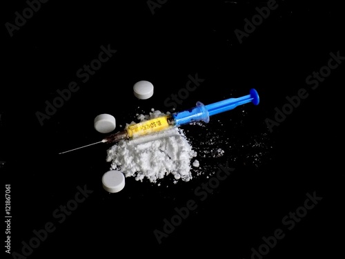 Cocaine drug powder pile, pills and injection on black background