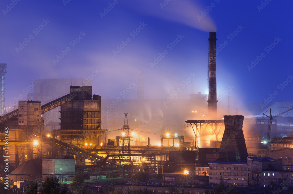 Metallurgical plant at night. Steel factory with smokestacks. Steelworks, iron works. Heavy industry in Europe. Air pollution from smokestacks, ecology problems. Industrial landscape at dusk. Plant