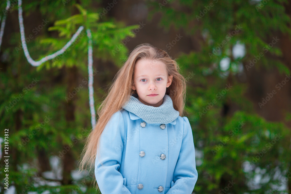 Portrait of little adorable girl in blue coat and mittens standing near the decorated Christmas tree on frosty winter day outdoor Portrait of little adorable girl in blue coat and mittens standing near the decorated Christmas tree on frosty winter day outdoor