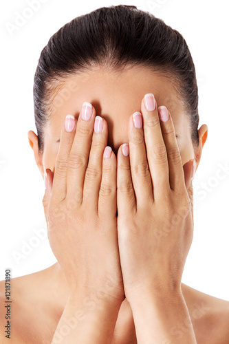 Young woman covering her face with her hands.