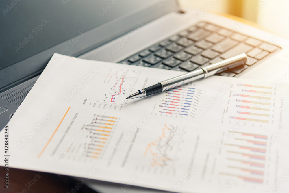 financial documents and pen on laptop with sunlight filter effect. financial documents and pen on laptop with sunlight filter effect.