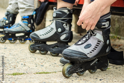 People friends putting on roller skates outdoor.