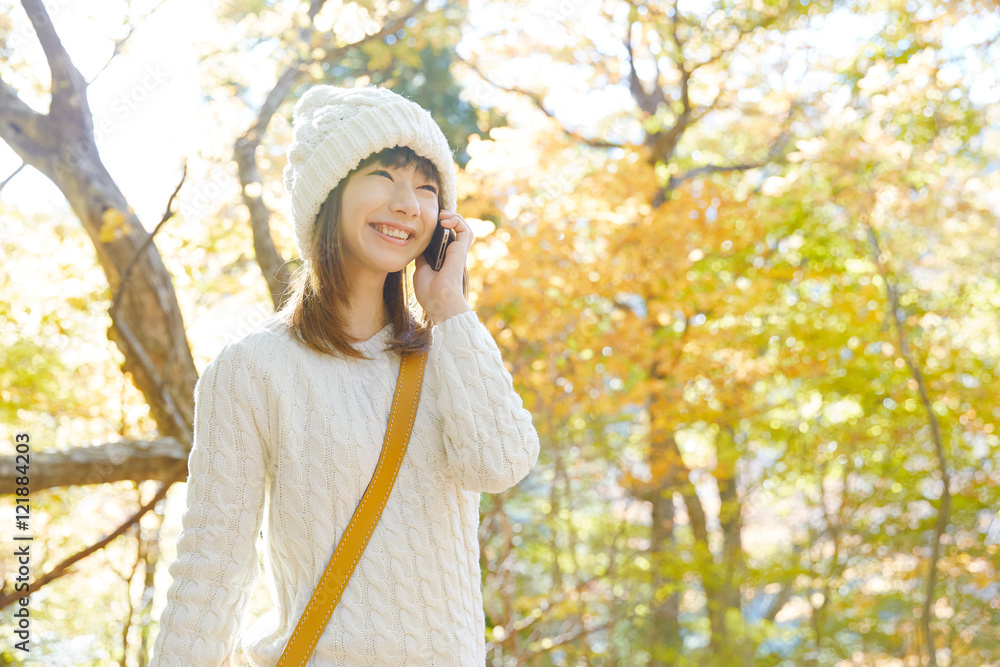 スマートフォンで話す女性 紅葉背景 スマートフォンで話す女性 紅葉背景