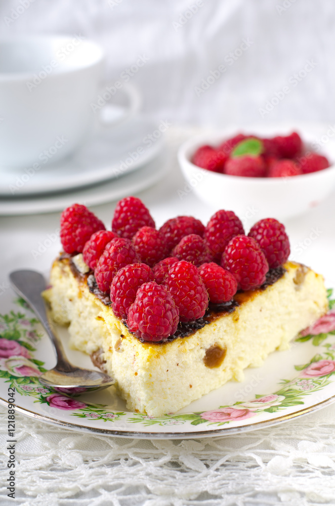 Cheesecake, souffle, cream mousse, pudding dessert with fresh raspberries and mint leaves on a white plate Cheesecake, souffle, cream mousse, pudding dessert with fresh raspberries and mint leaves on a white plate
