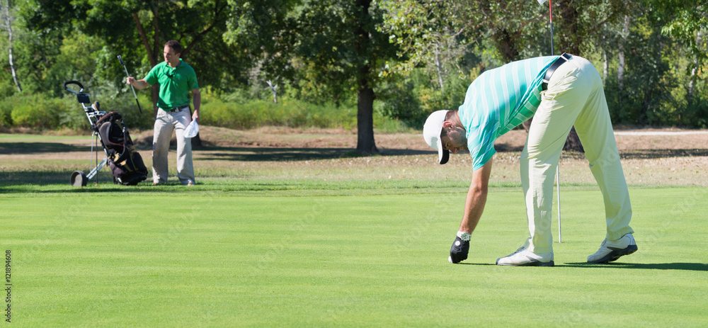 Obraz premium Golfer and caddy on the putting green