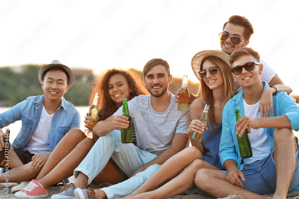 Obraz premium Group of friends hanging out with beer at the beach