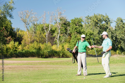 Golf. Golfer taking club from caddy