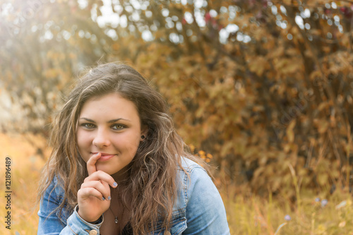 Portrait of pensive smiling teenage girl outdoors. Photo is edited on autumn colors.