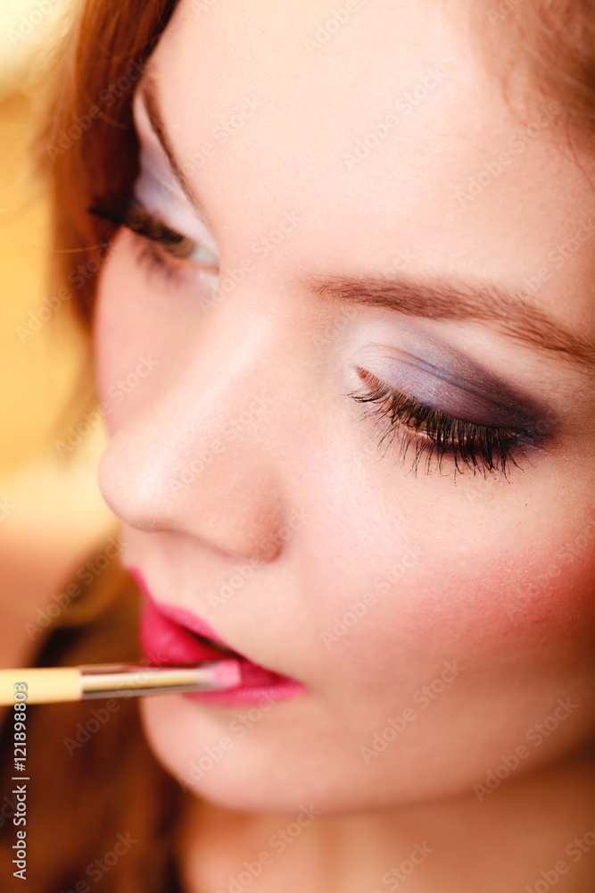 Part of face. Woman applying pink lipstick with brush Part of face. Woman applying pink lipstick with brush