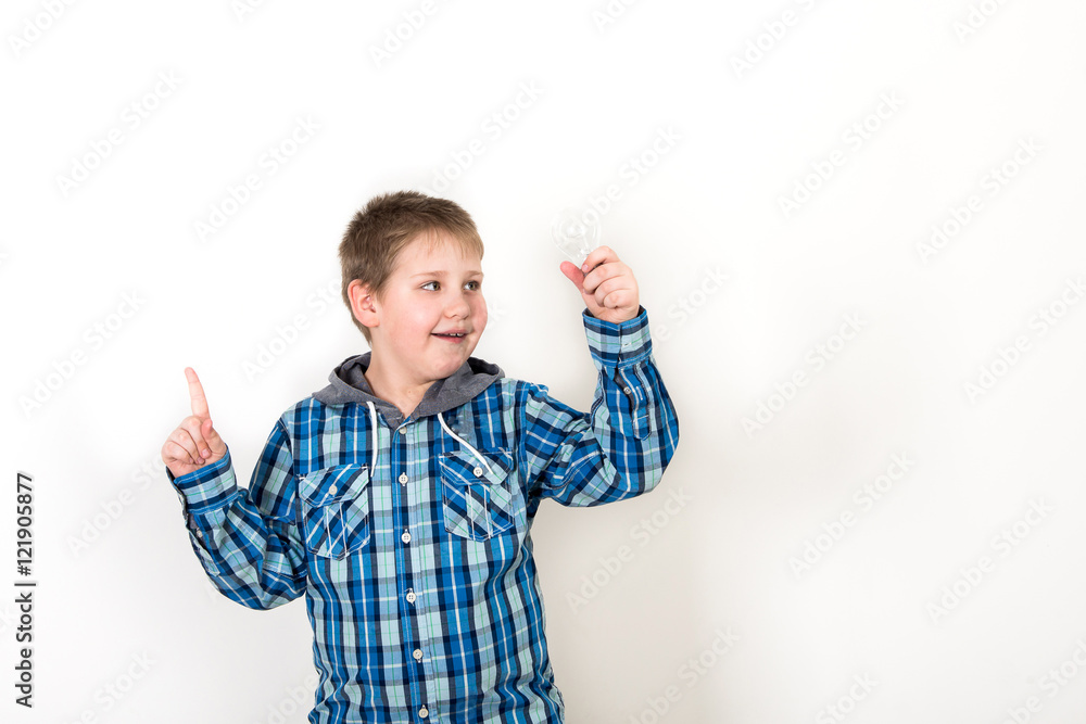 Smiling child holding tablet PC in hands. Idea concept. Photo shoot in the studio boy with tablet and a bulb-to-day knowledge Smiling child holding tablet PC in hands. Idea concept. Photo shoot in the studio boy with tablet and a bulb-to-day knowledge