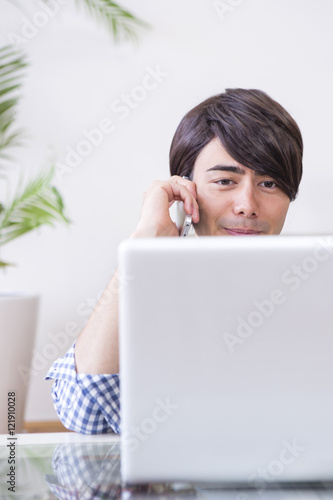 パソコンをしながら電話する男性