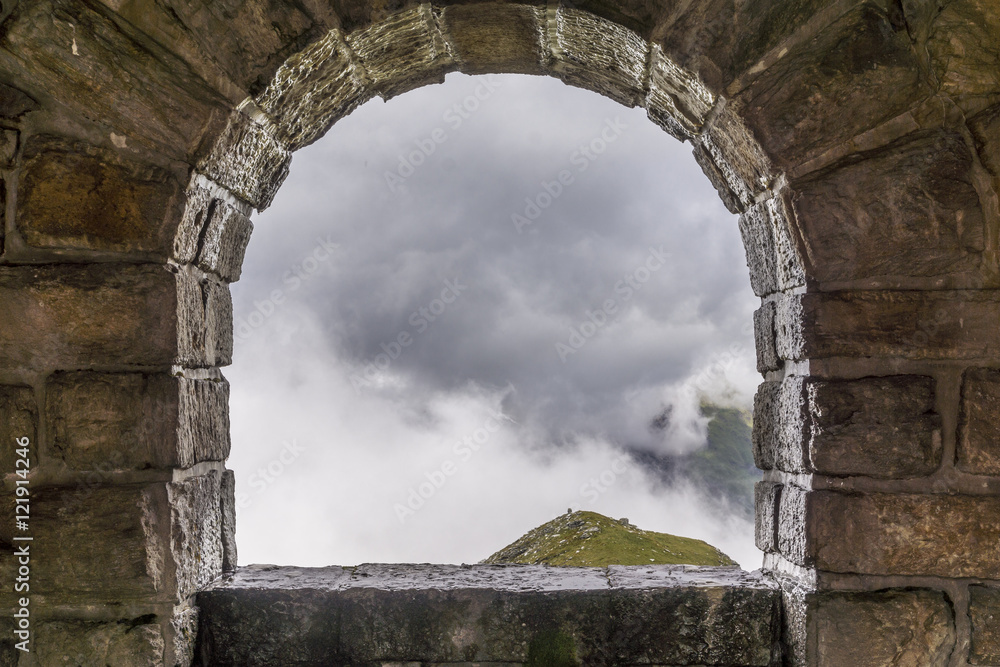 Blick durch einen steinernen Fensterbogen in die Wolkenfront