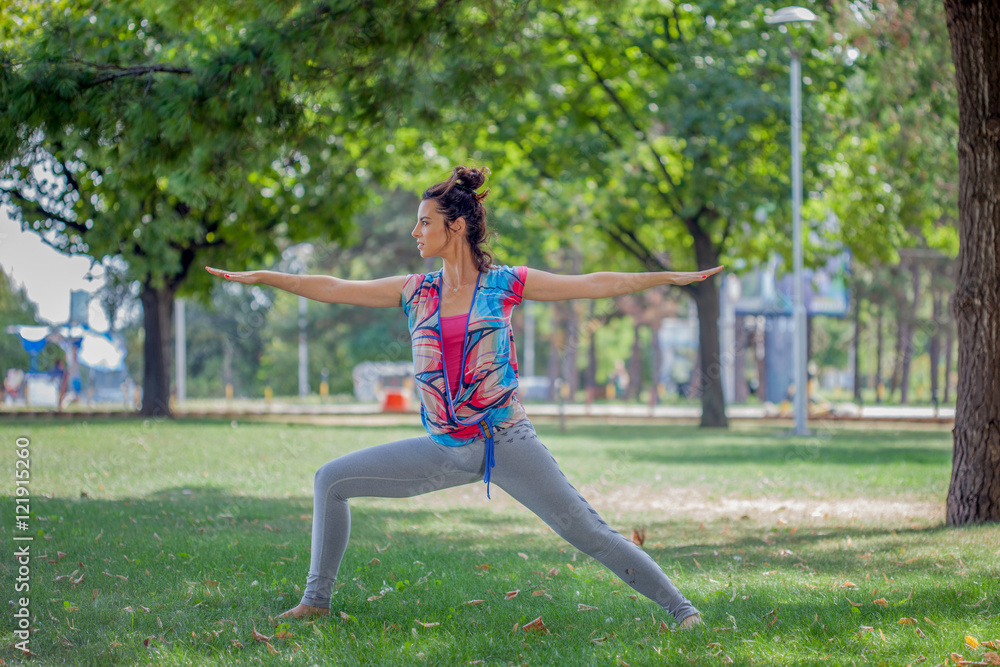 Young woman practicing yoga in the park on the green grass with Young woman practicing yoga in the park on the green grass with