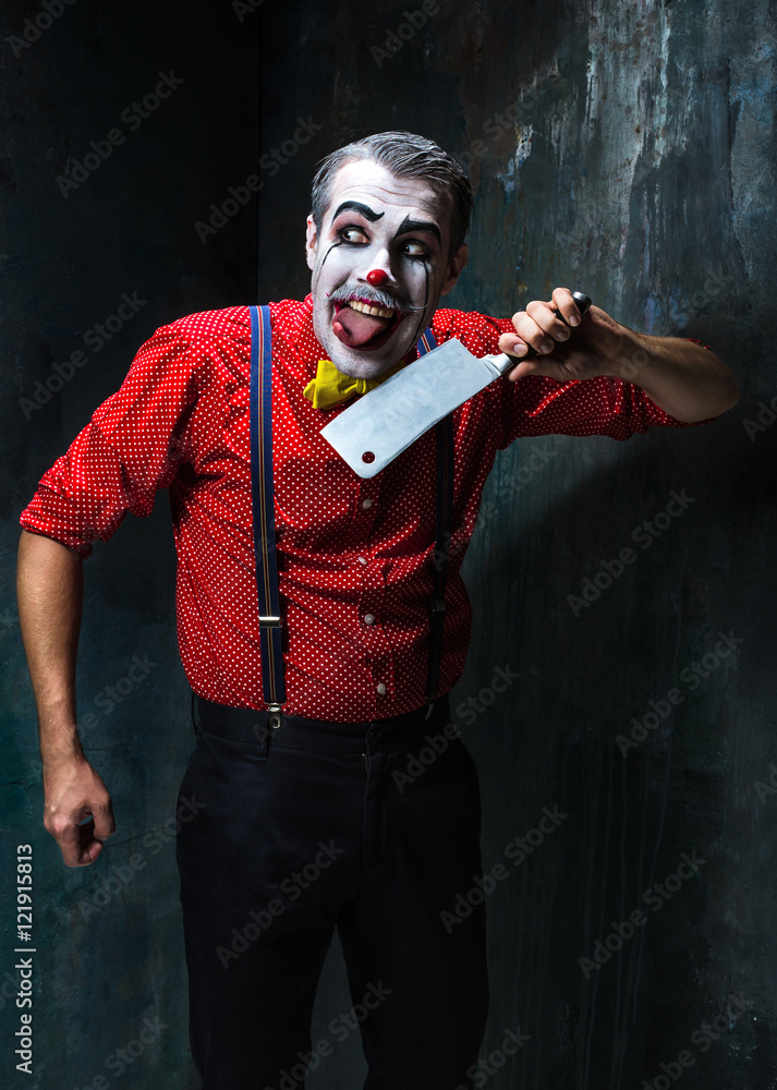 The crazy clown holding a knife on dack. Halloween concept