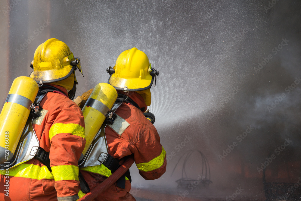 Fototapeta premium 2 firefighters spraying water in fire fighting operation