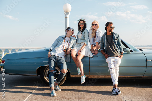 Smiling friends standing near cabriolet