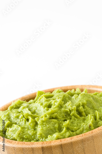 Guacamole in a wooden bowl isolated on white background 