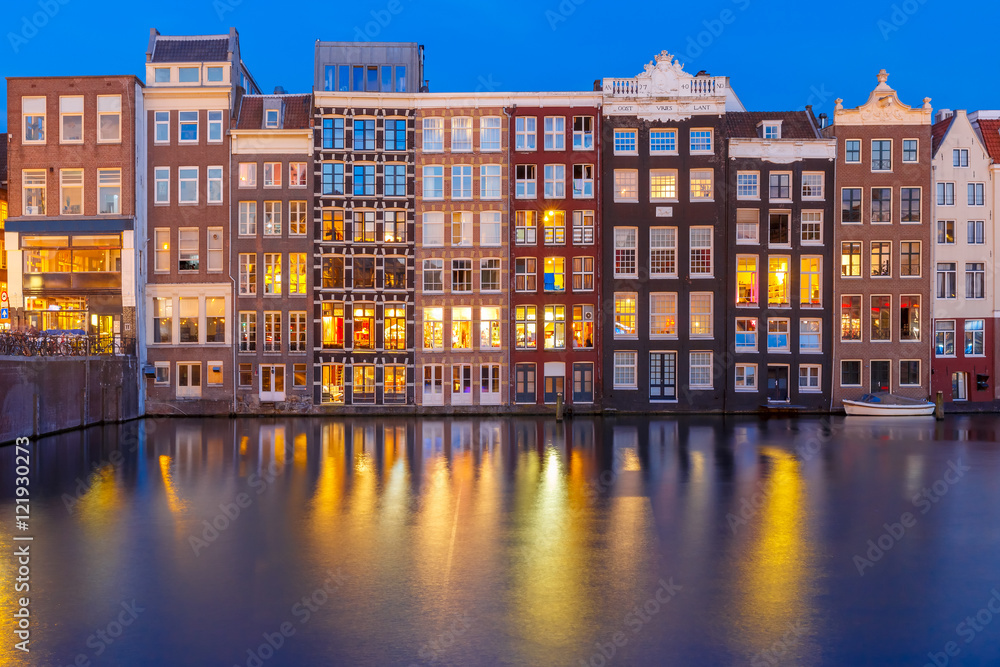 Beautiful typical Dutch dancing houses at the Amsterdam canal Damrak at night, Holland, Netherlands.