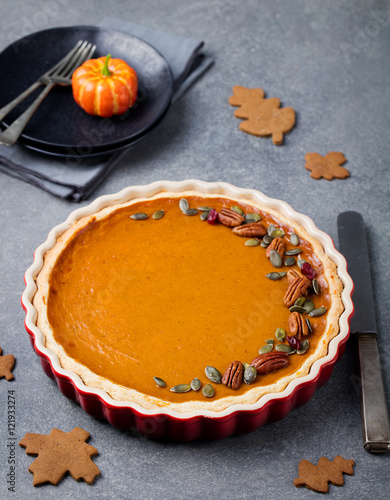 Pumpkin pie, tart made for Thanksgiving day in a baking dish Grey stone background.