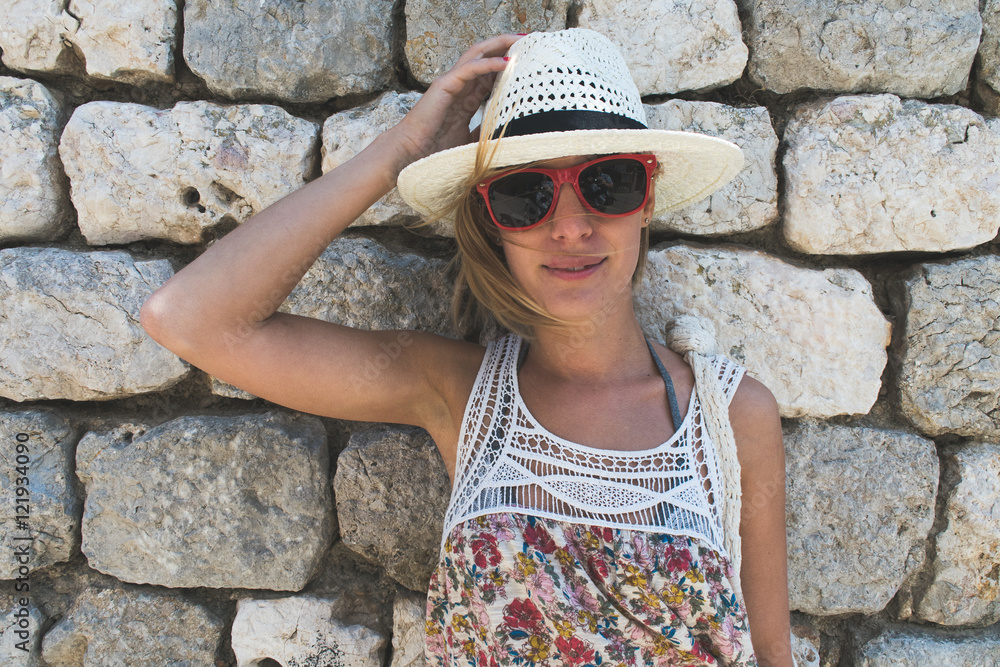 Young woman posing against stone wall on vacation Young woman posing against stone wall on vacation