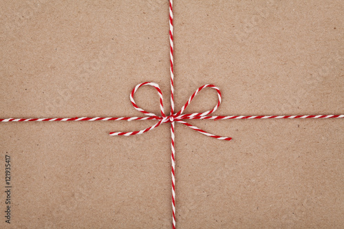 Christmas string or twine tied in a bow on kraft paper texture photo